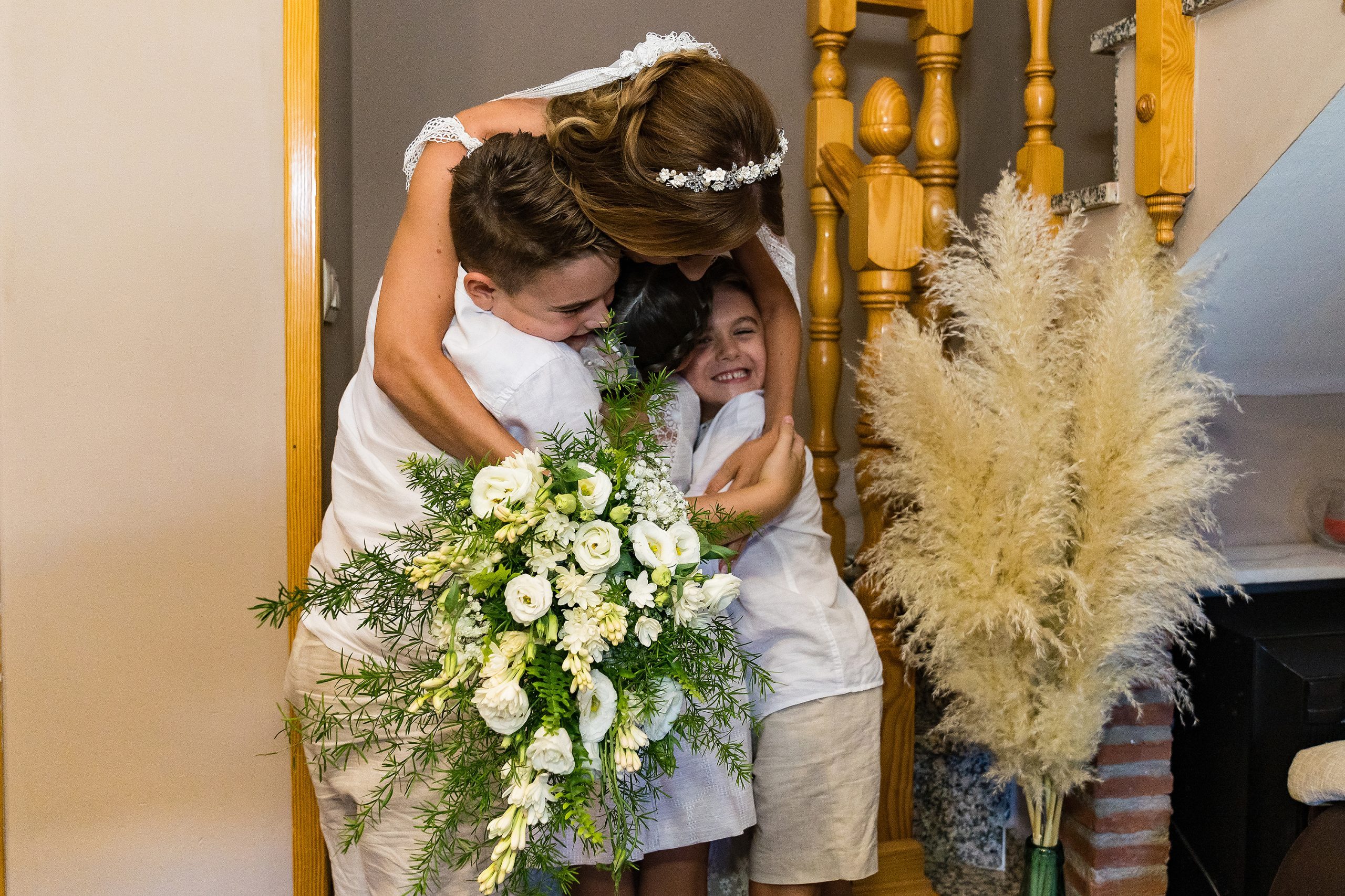 La novia abrazando a tres niños pequeños después de bajar por las escaleras