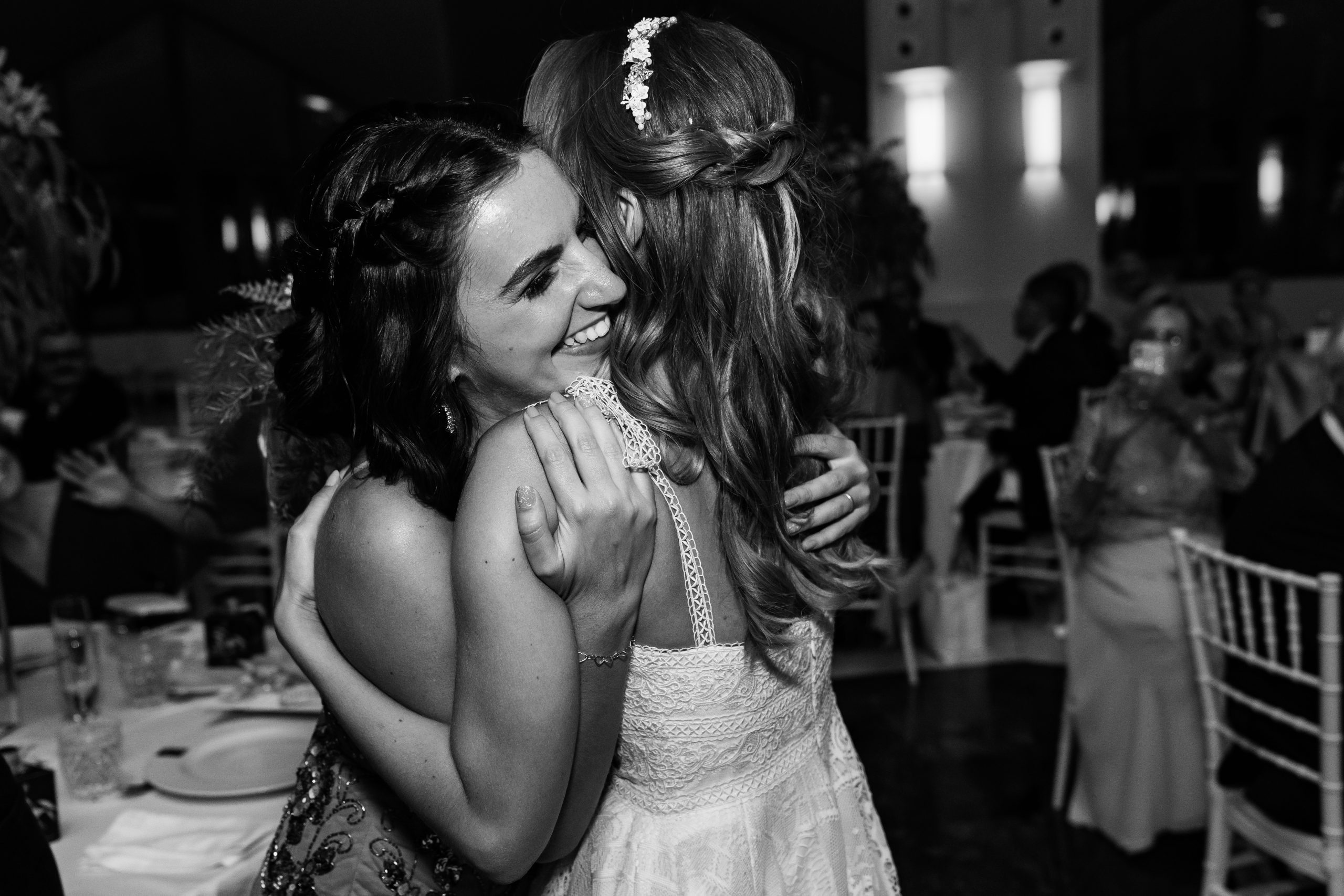 Foto en blanco y negro de la dama de honor y la novia abrazándose en el banquete