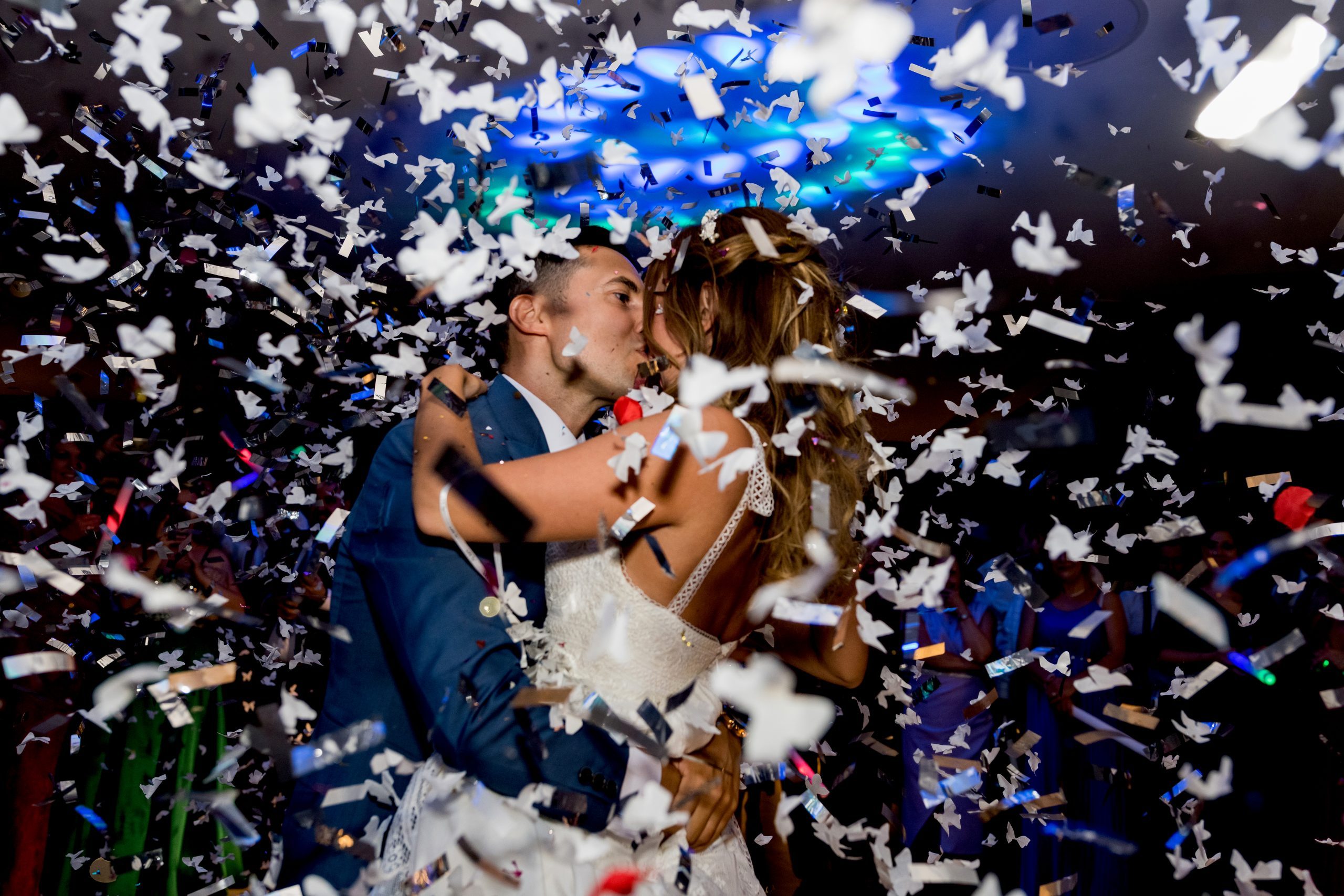 Los novios besándose bajo un montón de confeti de color blanco que caen como copos de nieve