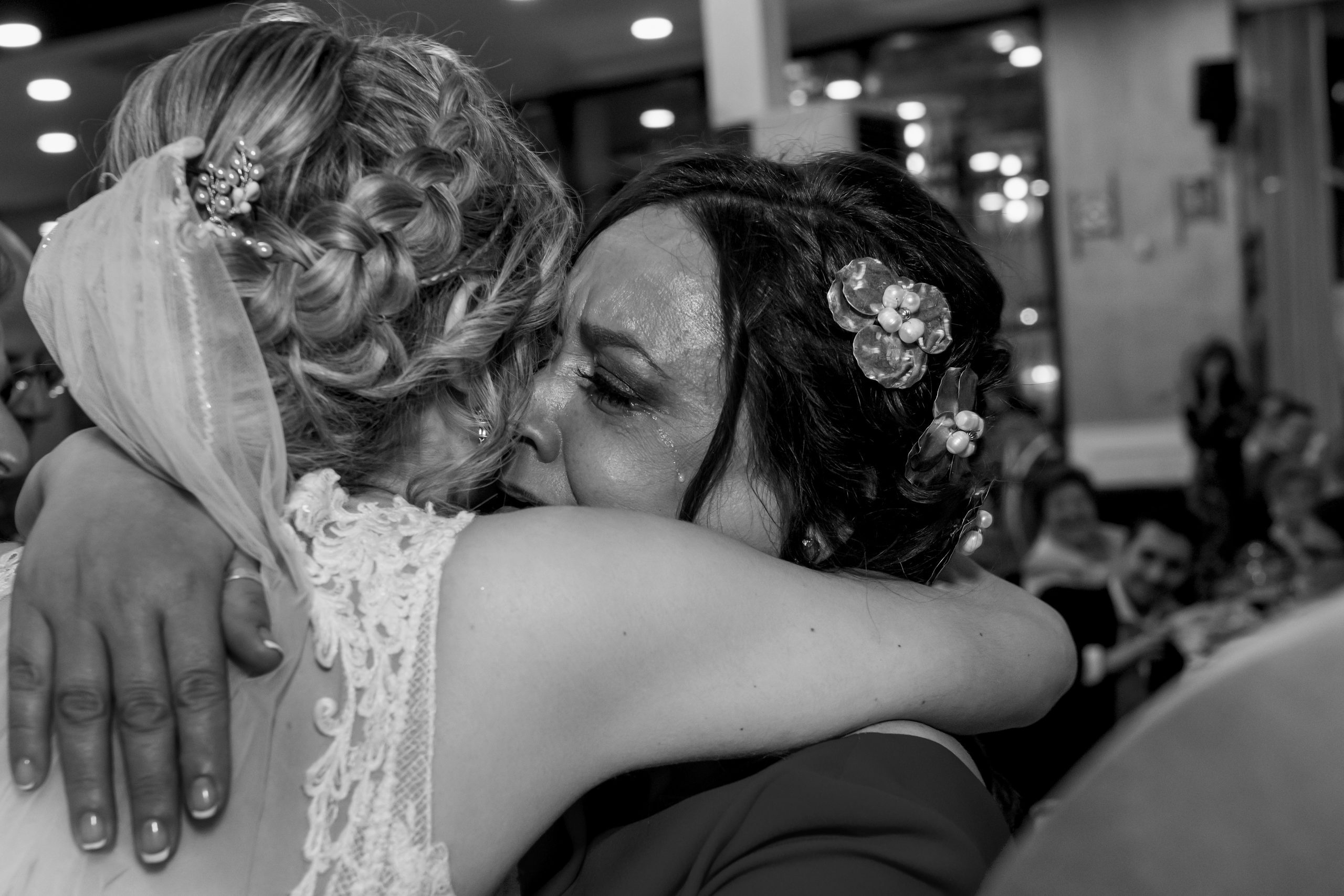 Foto en blanco y negro de la madre de la novia llorando mientras la abraza