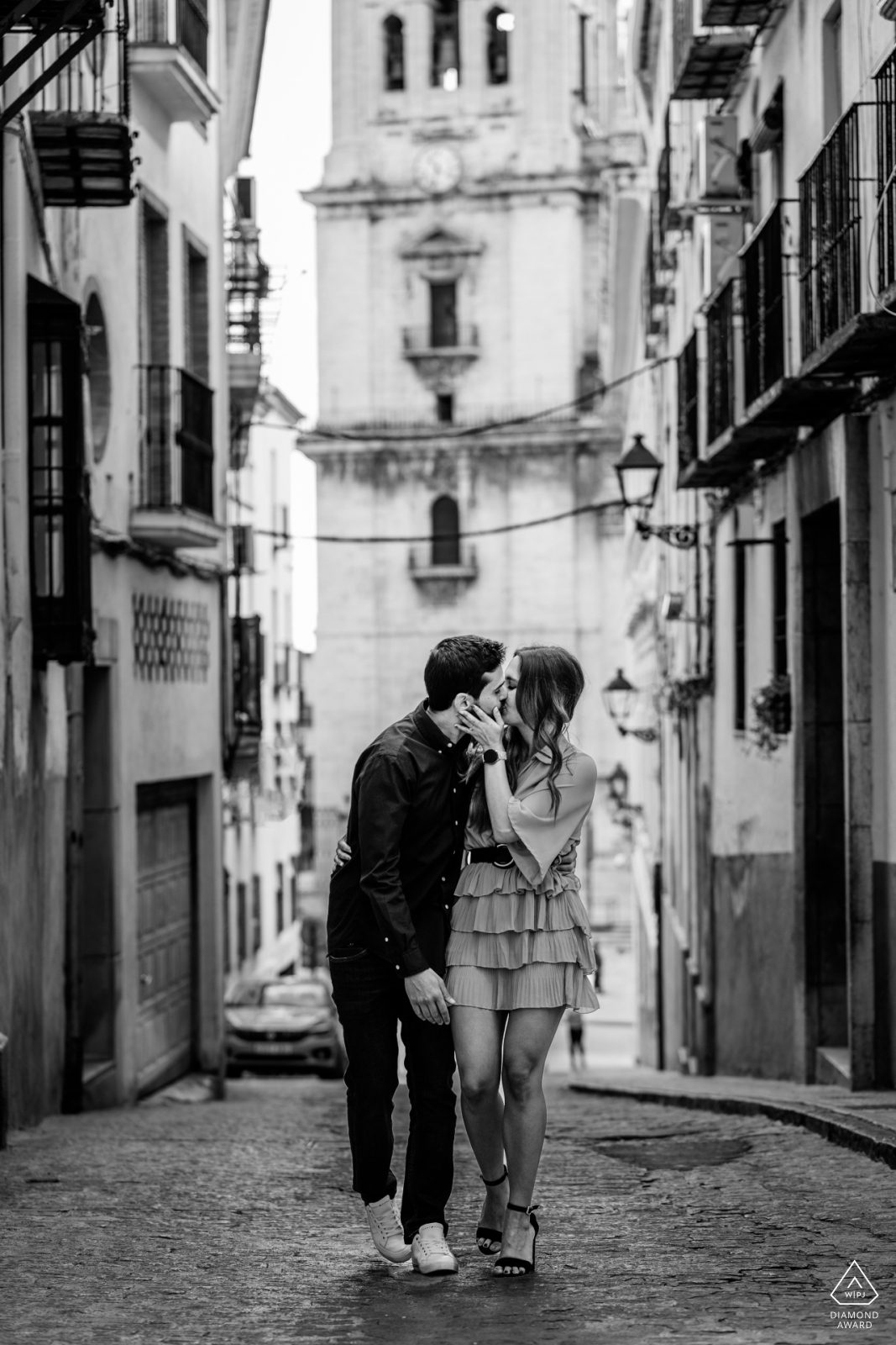 Fotografía en blanco y negro de una pareja besándose por las calles de una ciudad