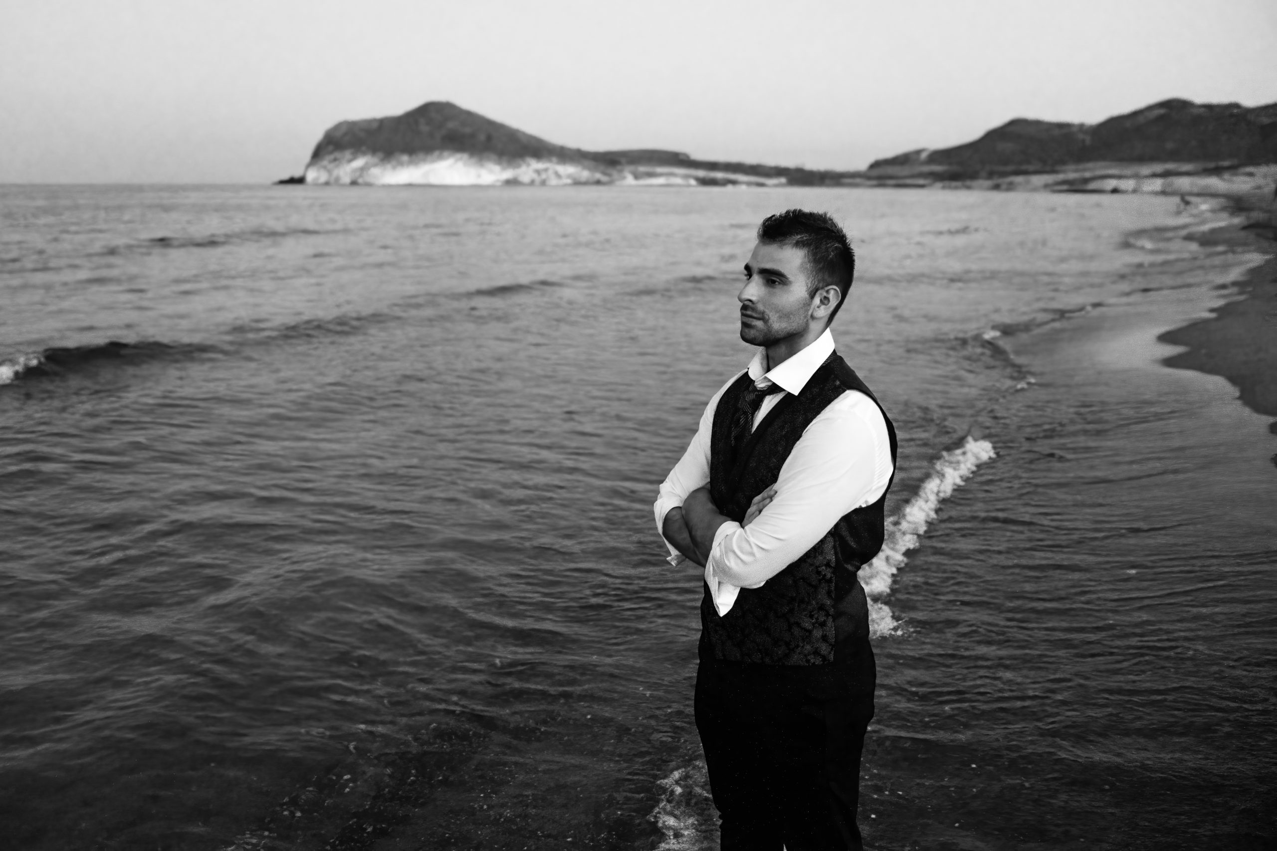 Foto en blanco y negro del novio mirando el mar desde la orilla