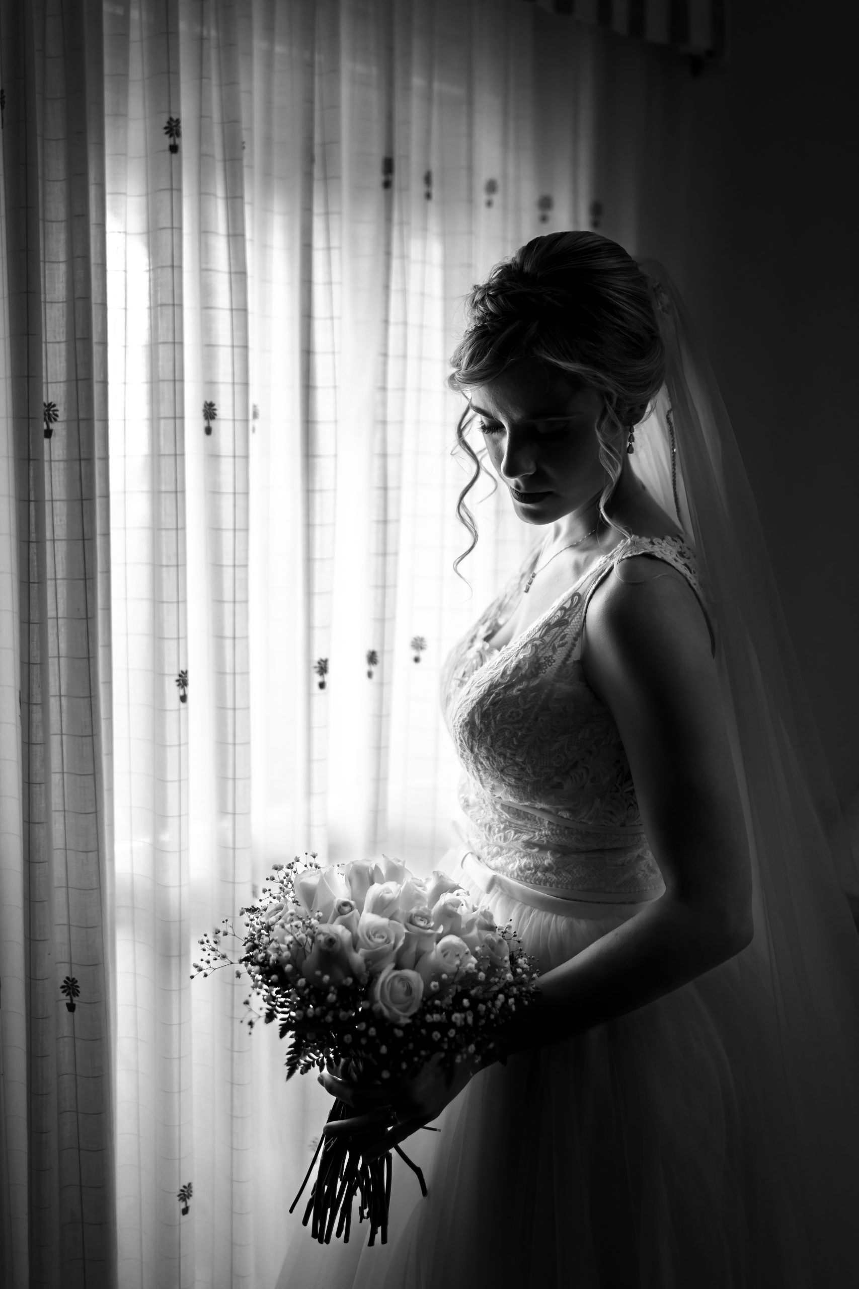 Fotografía en blanco y negro de la novia cerca de la ventana