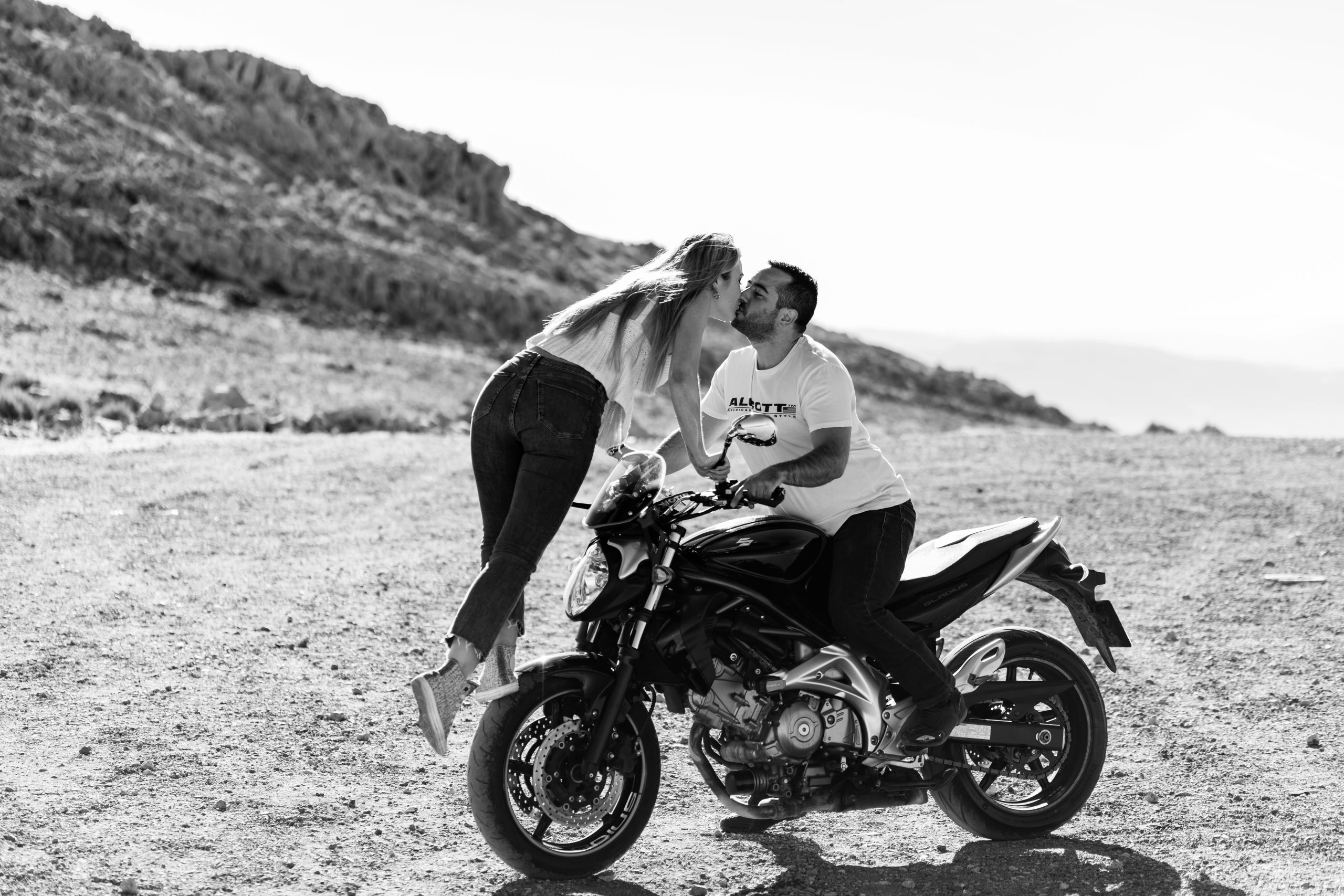 Fotografía en blanco y negro de una pareja besándose encima de una moto