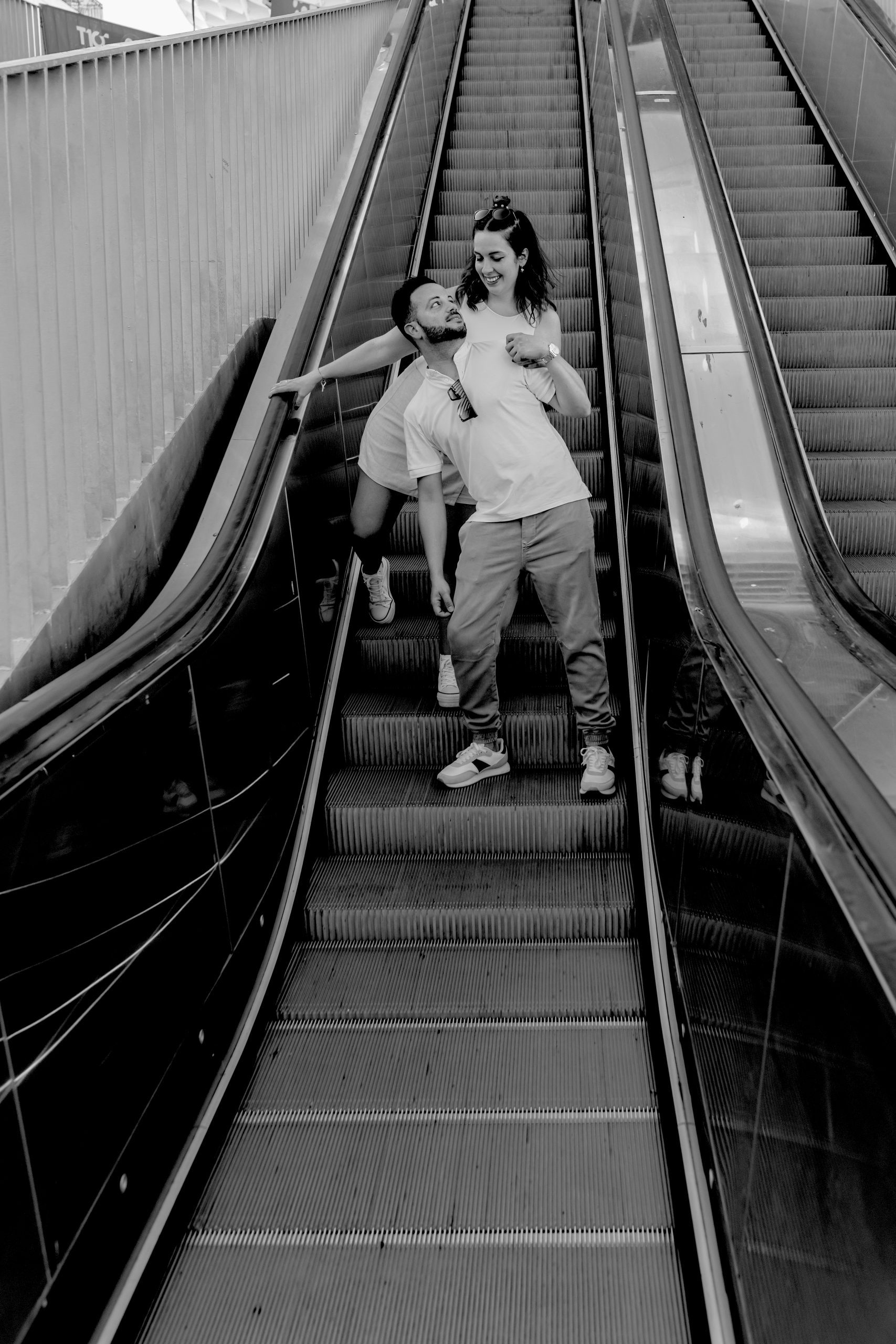 Fotografía en blanco y negro de una pareja en las escaleras mecánicas