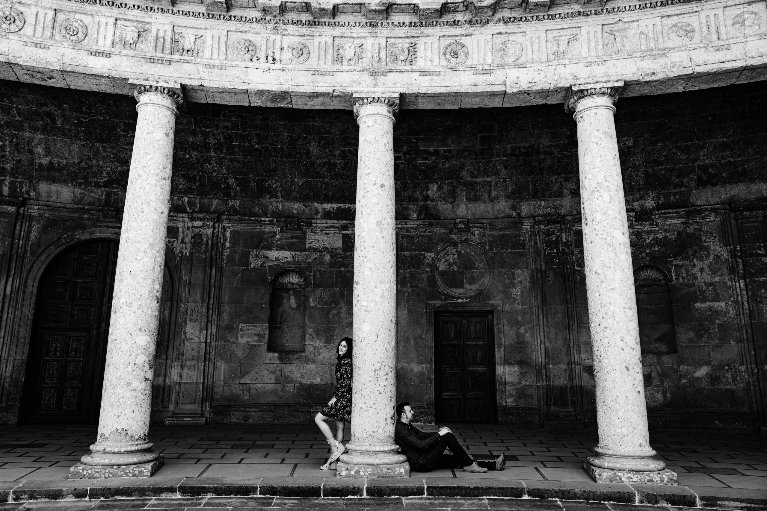 Fotografía en blanco y negro de una pareja apoyándose en una columna