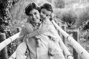 hermanos jugando a caballito en un puente en blanco y negro