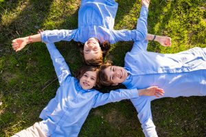 tres ninos tumbados en la hierba riendo al aire libre