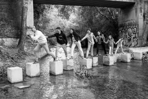 familia cruzando piedras sobre el agua en blanco y negro