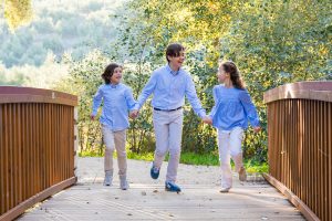 Sesión familiar en Jaén: niños corriendo por un puente en la naturaleza